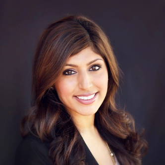 A placeholder woman with long, wavy brown hair and a friendly smile poses against a dark background. She is wearing a dark blazer.