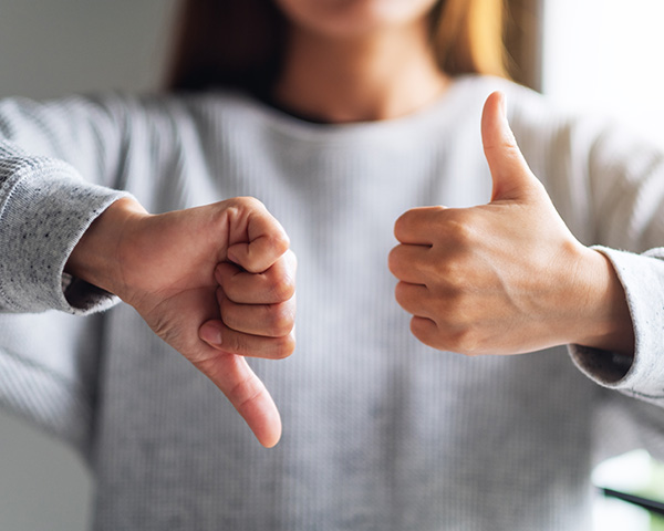 Closeup image of a woman making thumbs up and thumbs down hands sign