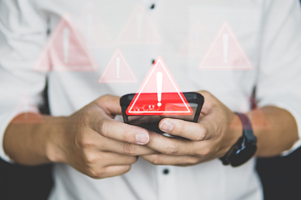 Person holding a smartphone with red warning symbols superimposed on the image.