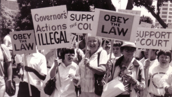 A black and white photo of a group of people holding up signs in a rally