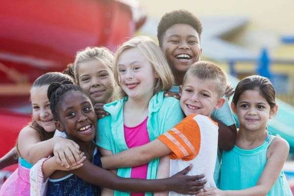 Girl with down syndrome, friends at water park hugging