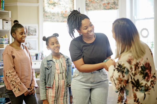 Parent and educator shaking hands in classroom with kids smiling