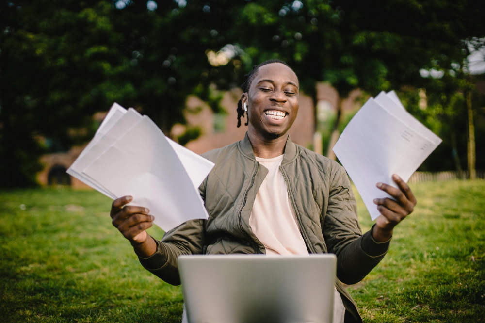 Man smiling with paperwork and laptop