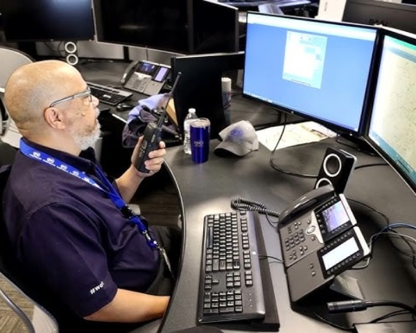 Man talks into walkie talkie in front of his office computer